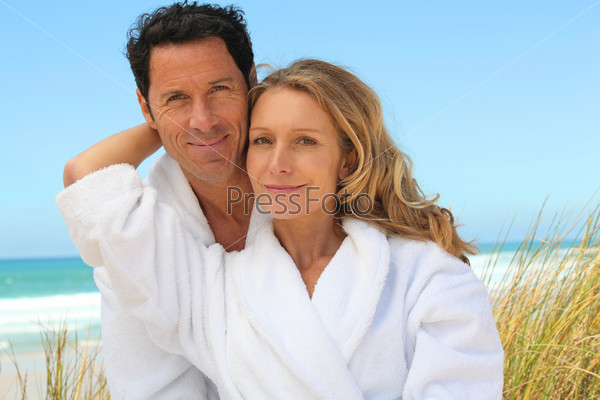 Couple relaxing on the beach in toweling robes