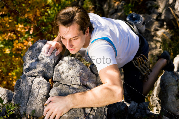 Climber trying to get over a rock nose, autumn setting