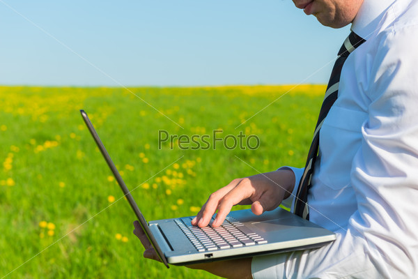 Man in a tie with laptop in nature, stock photo