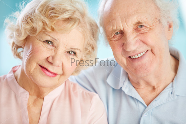 Close-up portrait of a charming elder couple looking at the viewer with a smile, stock photo