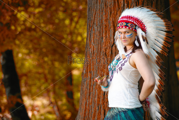 Young woman in war bonnet headdress of American Indian smokes a pipe