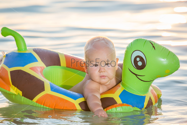 Baby bathing in the sea with swim ring