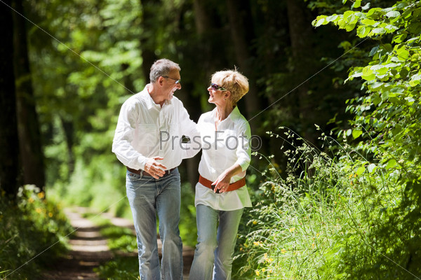 Mature or senior couple deeply in love having a walk holding each other tight in late spring or early summer