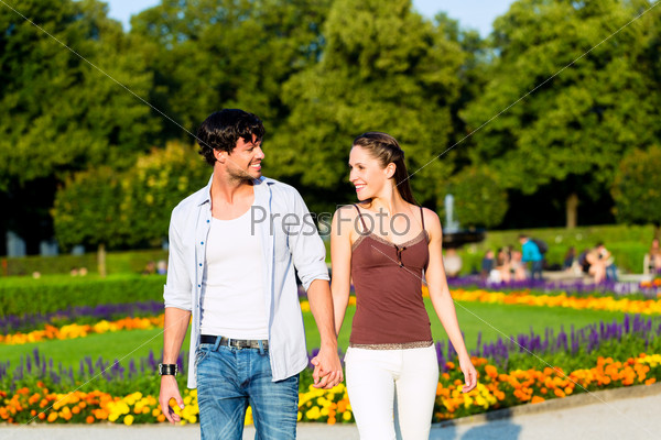 Man and woman or young couple making a trip as tourists in park waling hand in hand