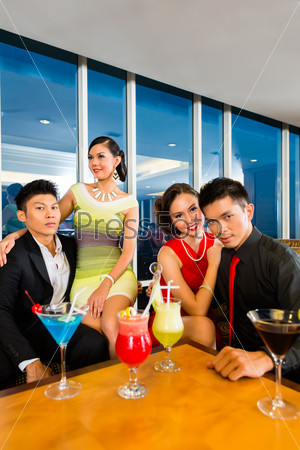 Young and handsome Asian Chinese people drinking cocktails in a luxurious and fancy lounge bar drinking cocktails , stock photo