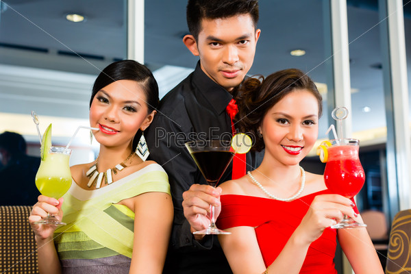 Young and handsome Asian Chinese people drinking cocktails in a luxurious and fancy lounge bar drinking cocktails