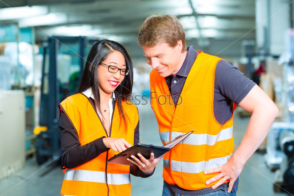 Logistics Teamwork - Worker or warehouseman and his female coworker with tablet computer at warehouse of freight forwarding company
