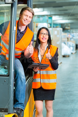 Logistics Teamwork - forklift driver, Worker or warehouseman and his coworker with tablet computer at warehouse of freight forwarding company
