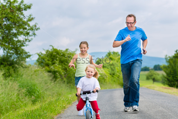 Family activity - Little girl and their father or dad running on street in rural environment