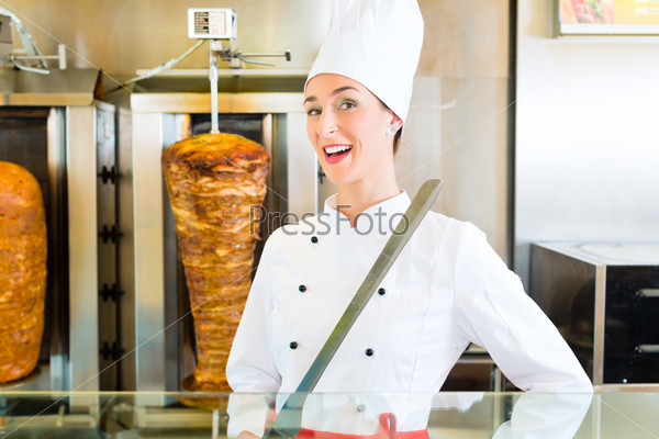 Doner kebab - friendly vendor in a Turkish fast food eatery, whit sharp knife in front of skewer