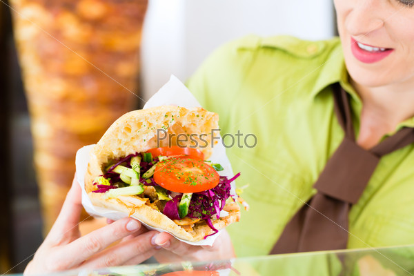 Doner kebab - friendly vendor in a Turkish fast food eatery, with a freshly made pita bread or kebab in front of skewer