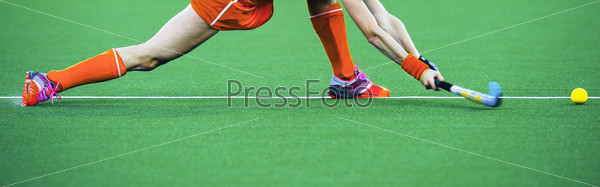 Female athlete field hockey player performing a stretched drag flick on an artificual grass pitch