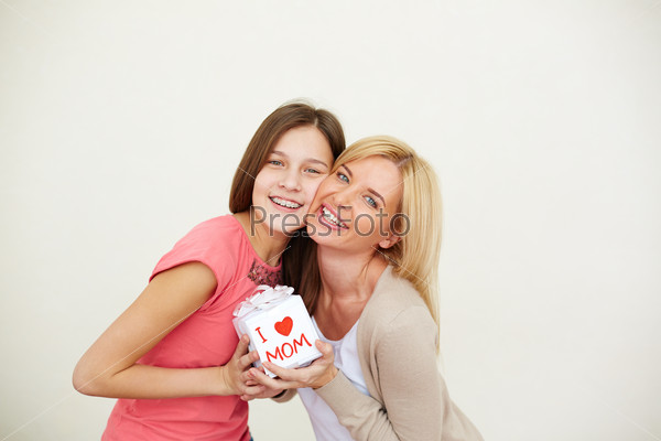 Teenage girl and her mom with small present looking at camera in isolation