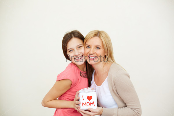 Teenage girl and her mom with small present looking at camera