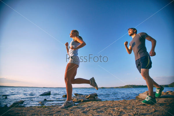 Photo of happy young dates running down coastline