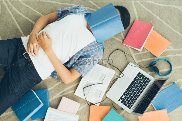 Exhausted student fall asleep with a textbook on his face