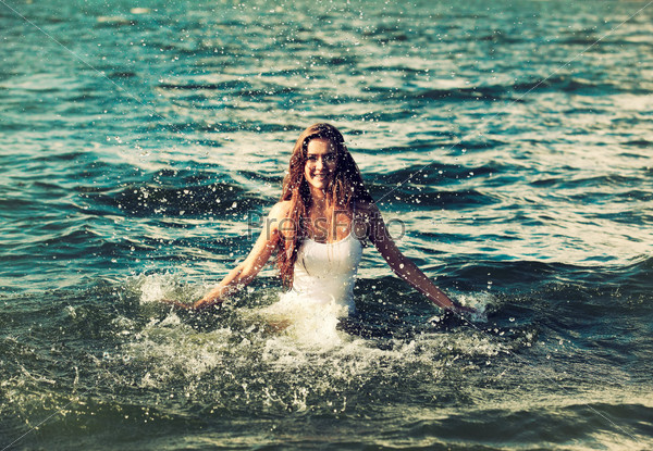 Colorized vintage outdoor portrait of Young beautiful slavonic girl in white top in sea water splashing