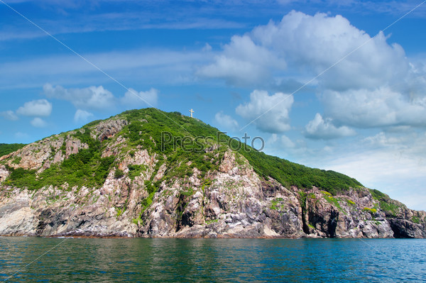 Rocks , sea and Orthodox crosson the  blue sky - Fox Island at the entrance to the port of Nakhodka Russia