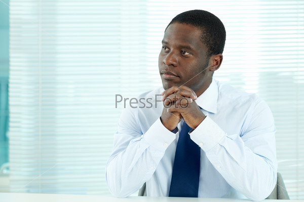 Portrait of pensive African businessman sitting in office, stock photo