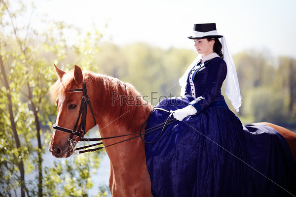 Lady on a horse. The lady on riding walk. Portrait of the horsewoman. The woman astride a horse. The aristocrat on riding walk.
