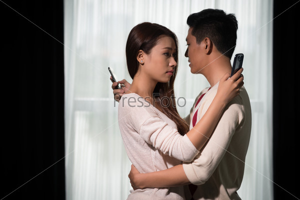 Asian boyfriend and girlfriend hugging each other but texting to other people