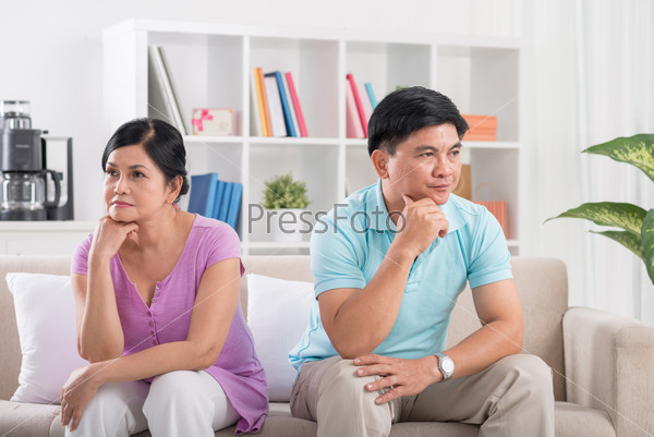 Unhappy married couple sitting on the sofa after having a quarrel
