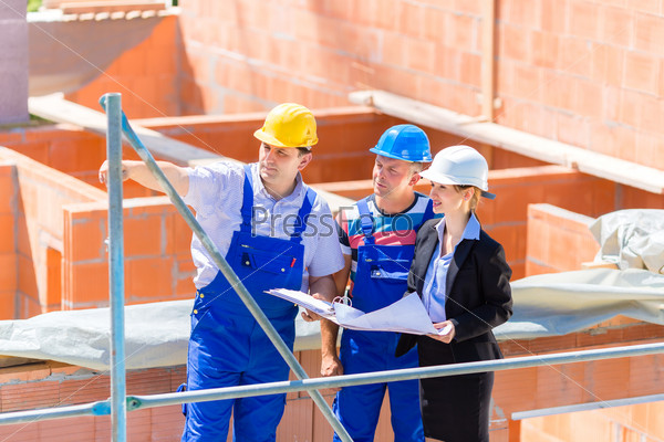 Construction site Team or architect and builder or worker with helmets discuss on a scaffold construction plan or blueprint or checklist , stock photo