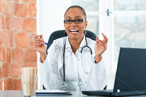 Young female black doctor sitting at a window in clinic, she has a stethoscope