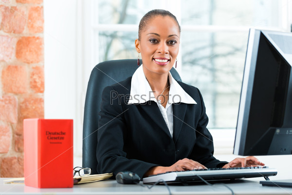 Young female lawyer working in her office with a typical law book and writing on the Computer