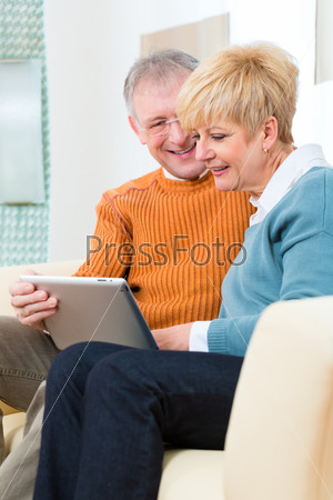 Пожилые люди дома с планшетным компьютером
