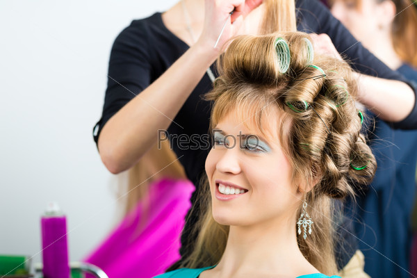 Hairdresser - hair stylist curling hairs, a female customer gets a haircut