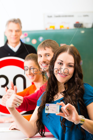 Driving school - driving instructor in his class and a female student driver looking in the Camera, in the background are traffic signs