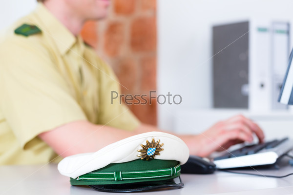Police officer in police station working on the computer, on a case or registering a complaint, stock photo