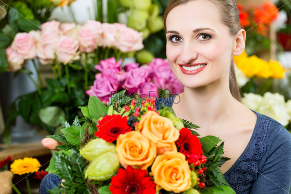 Female florist in flower shop or nursery presenting yellow roses