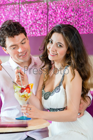 Young Couple in a Cafe or Ice cream parlor, eating an ice cream sundae together