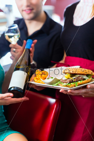 Friends or couple eating fast food in American fast food diner, the waitress serving the food and wine