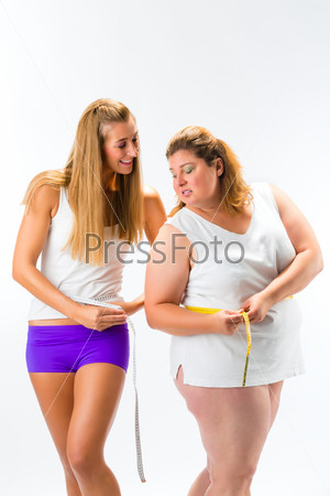 Thin and fat woman measuring waist with measuring tape, one woman looking unhappy or envious, studio shot isolated on white
