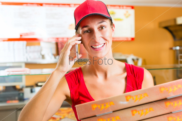 Woman working as delivery girl in a pizza place holding several pizza boxes smiling