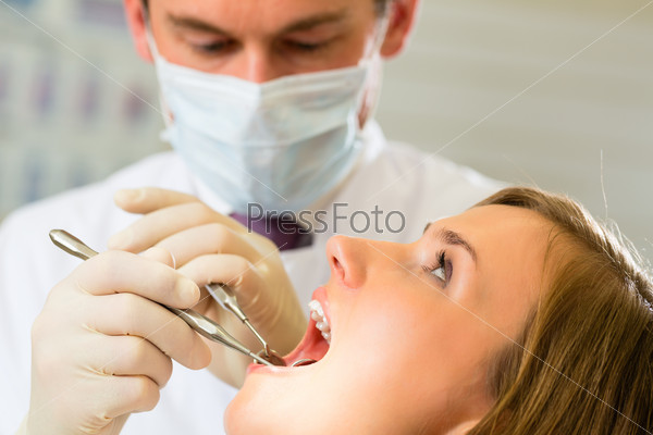 Female patient with dentist in a dental treatment, wearing masks and gloves, stock photo