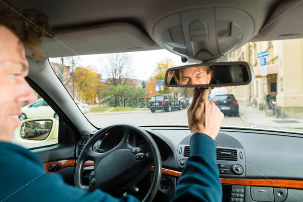 Опытный таксист смотрит в зеркало заднего вида и регулирует таксометр