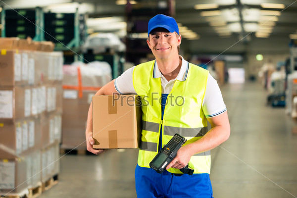 Warehouseman with protective vest and scanner, scans bar-code of package, he standing at warehouse of freight forwarding company