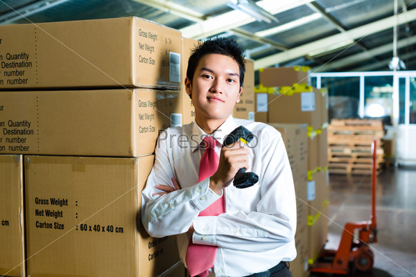 Young man in a suit with a bar code scanner in a warehouse