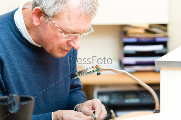 hearing aid acoustician at work, he is working on a hearing aid for hearing impaired persons