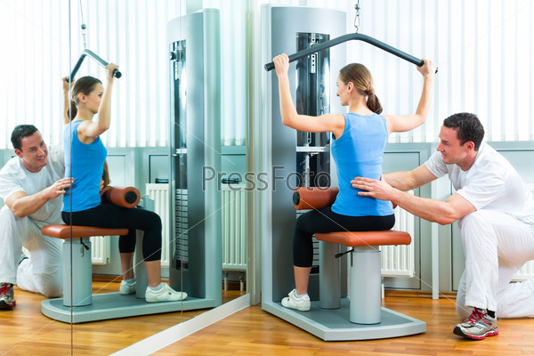 Patient at the physiotherapy or physical therapy doing exercises with her therapist