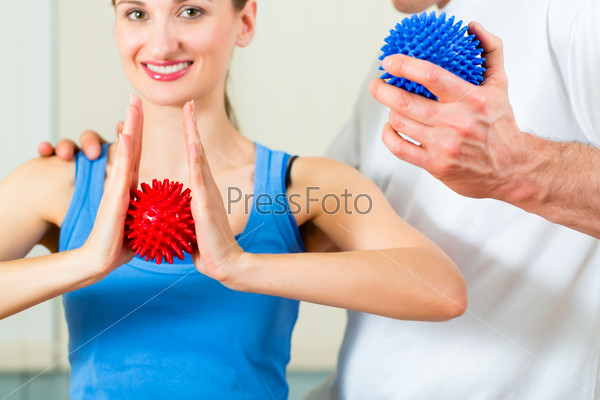 Female Patient at the physiotherapy doing physical exercises with her therapist, they using a massage ball