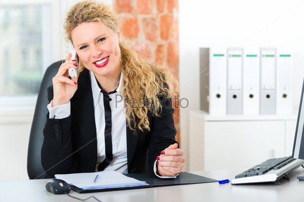 Young lawyer or secretary working in her Office, she sits on the desk and on the telephone is a customer or client, stock photo