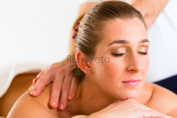 Woman enjoying a wellness back massage in a spa, she is very relaxed
