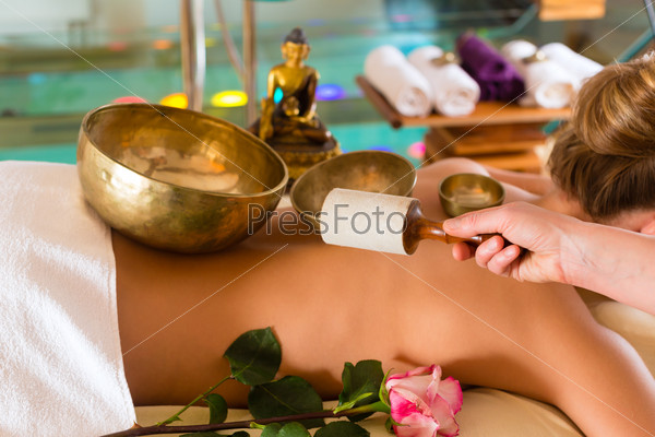 Woman in wellness and spa setting having a singing bowl massage therapy