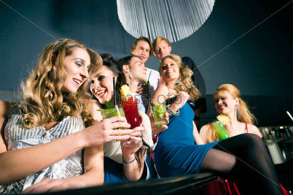 Young people in club or bar drinking cocktails and having fun