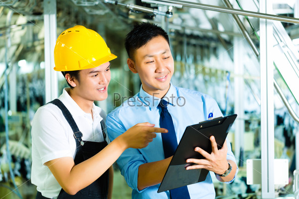 Worker or production manager and owner, ceo or controller, look on a Clipboard in a factory